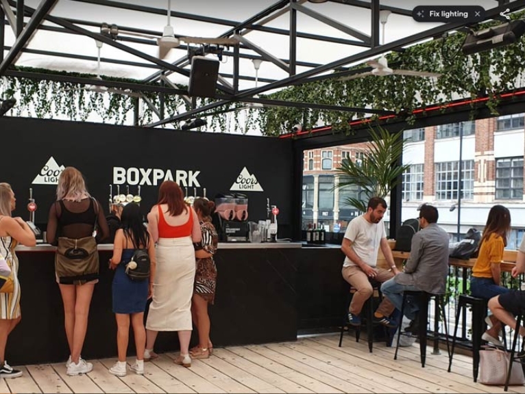 A photo of BOXPARK container bar in Shoreditch with people enjoying a beer.
