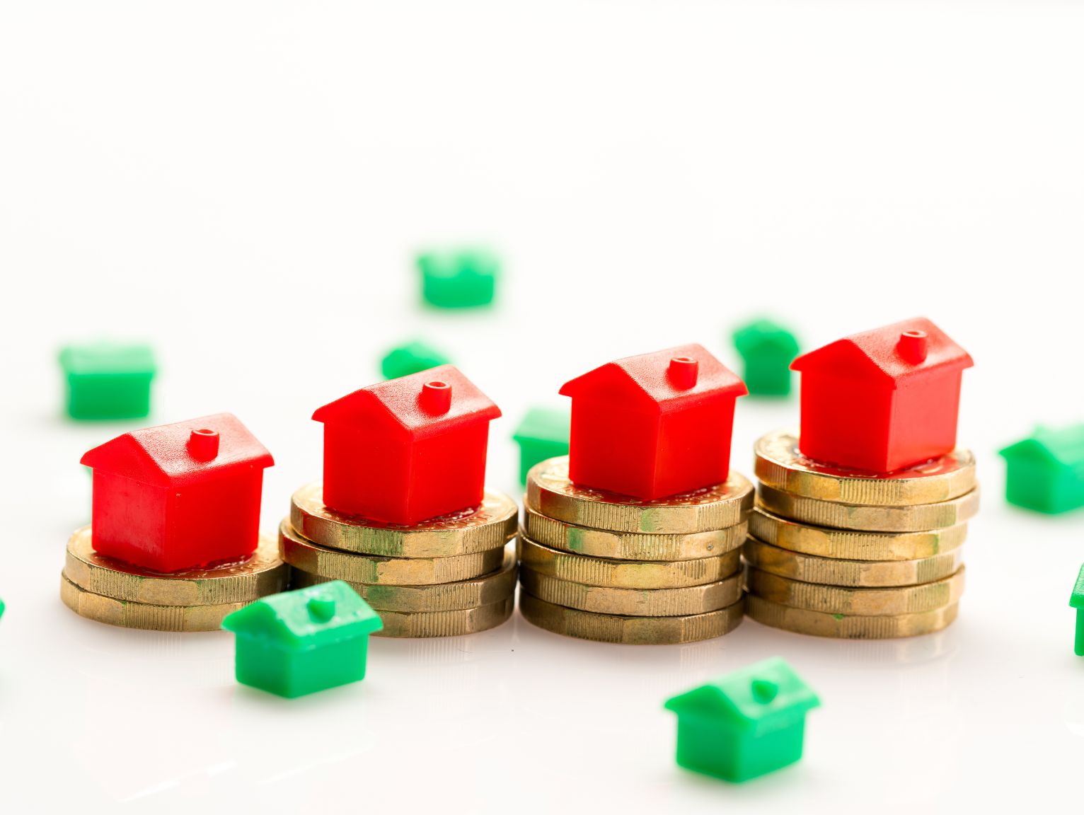 Building Safety Levy 2026: Four red toy houses stacked on rising piles of gold coins, with small green houses scattered around them against a plain white background.