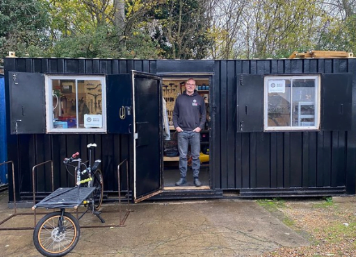 Rory Thomson stands in front of his shipping container bike repair shop