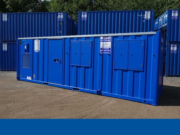 A single blue welfare unit in front of blue containers stacked