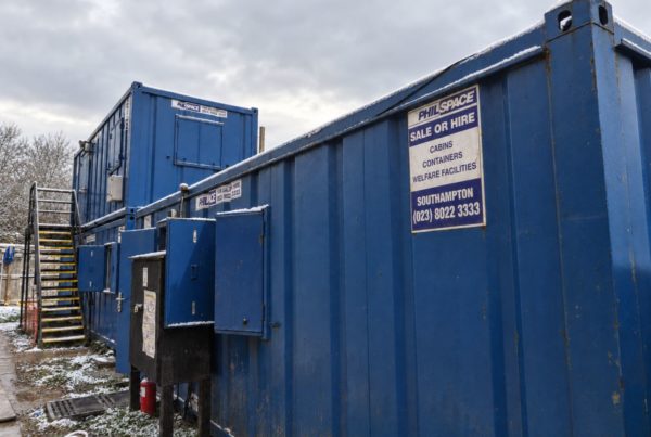 How Many Welfare Units Do I Need On-Site: Row of blue PhilSpace site cabins with “Sale or Hire” signs, external stairs and a light dusting of snow under a grey sky.