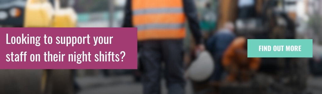 Construction workers wearing reflective vests are shown working at night under artificial lighting. The image is blurred with an overlaid banner message about supporting staff during night shifts.