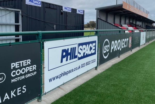 Philspace cabins set up pitchside at Sholing FC, with branding displayed along the railings.