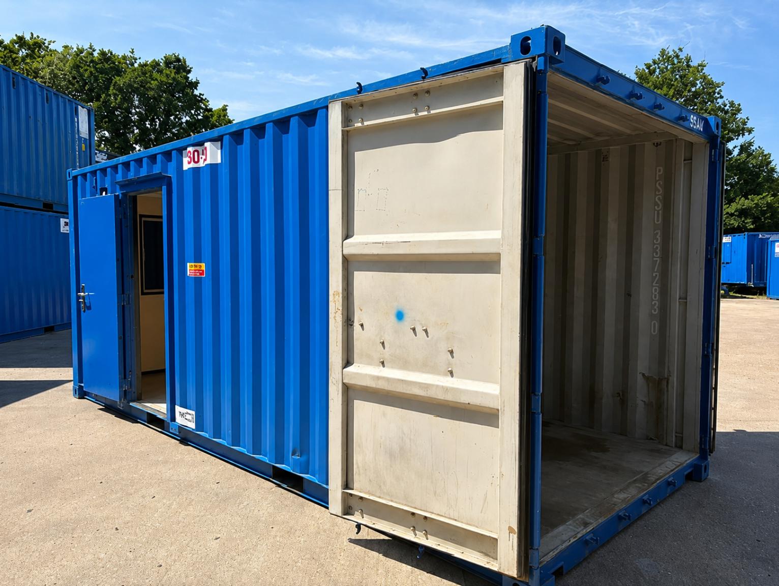 When to use a combined welfare and storage unit on site An empty blue shipping container with its double doors open, showing bare metal walls and a connecting door to an adjoining fitted-out unit.