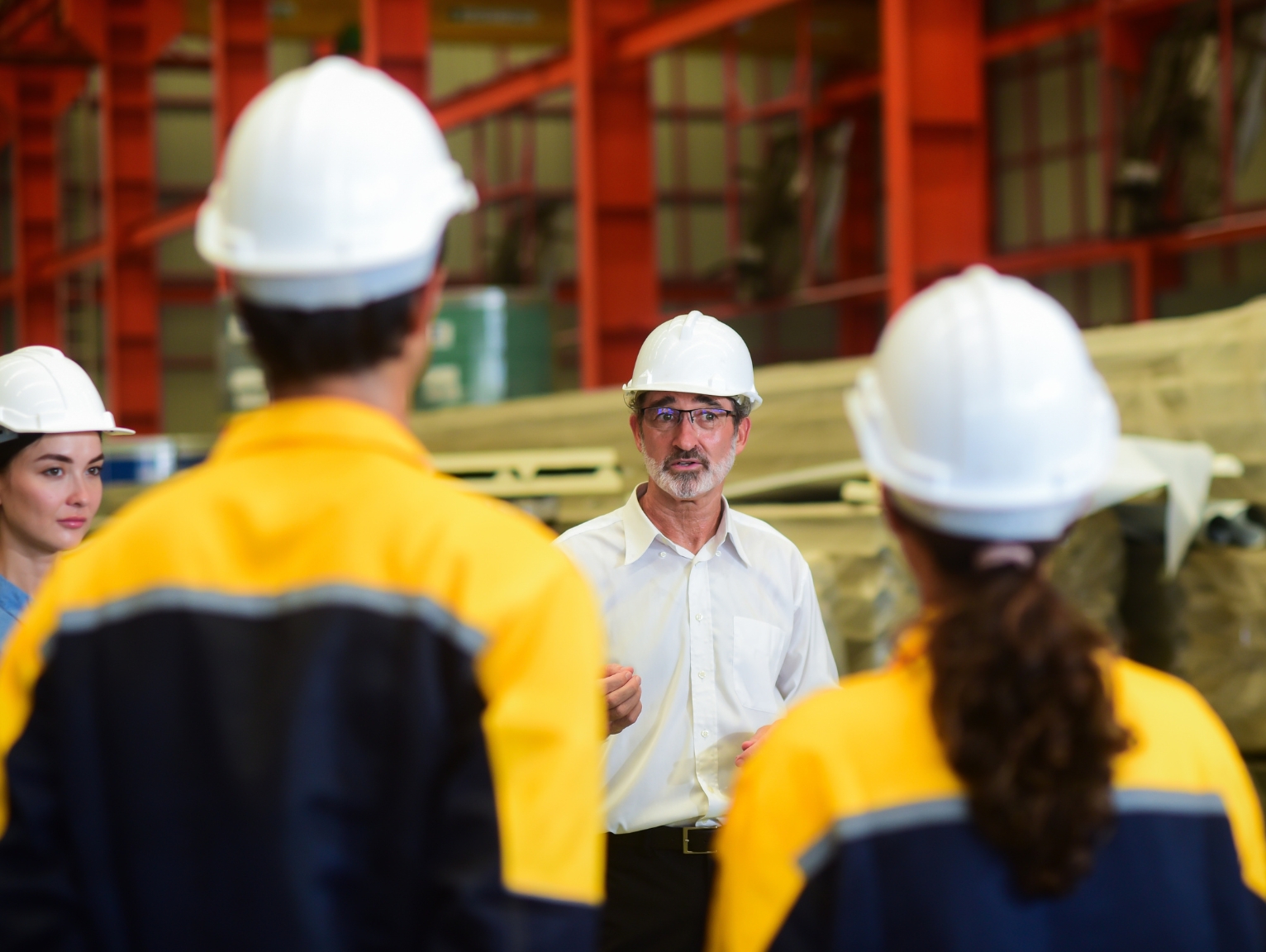 Construction site supervisor leading a safety or training briefing with workers in hard hats and high-vis jackets.