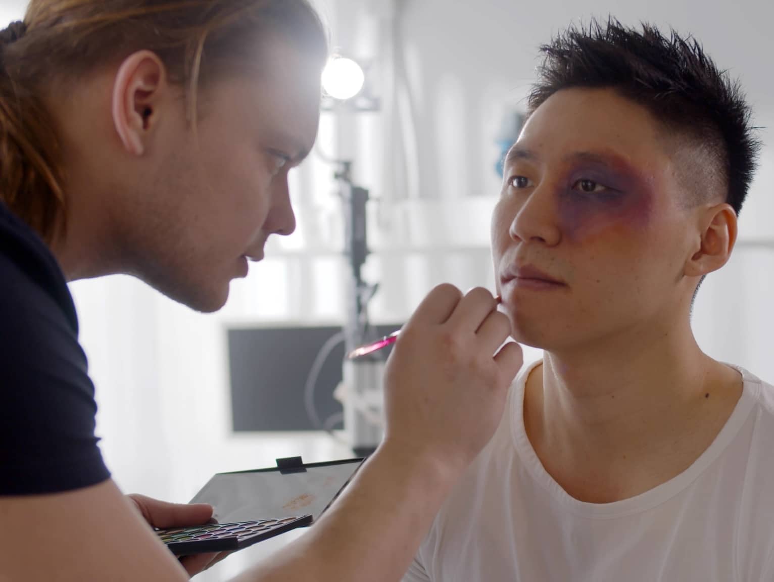 Makeup artist applying special effects makeup to actor’s face