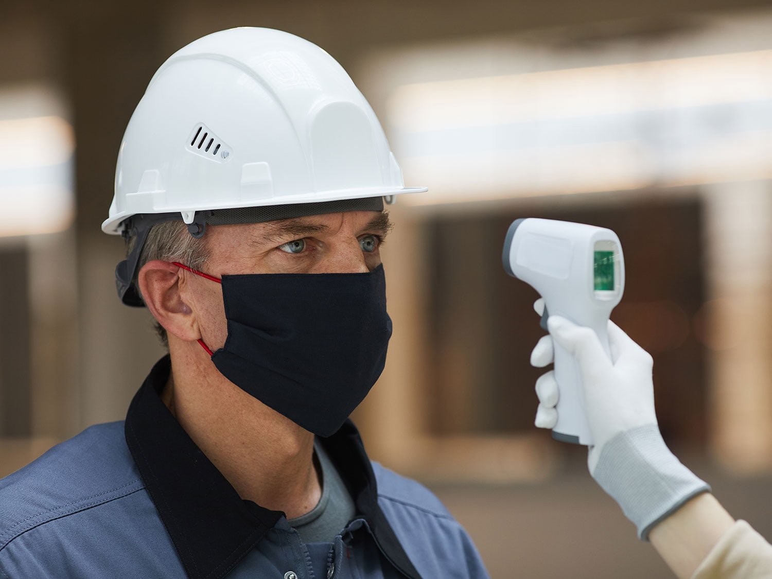 A construction worker gets a temperature check to test on-site for COVID-19