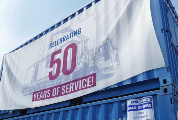 A philspace 50 years of service banner hanging over a blue shipping container