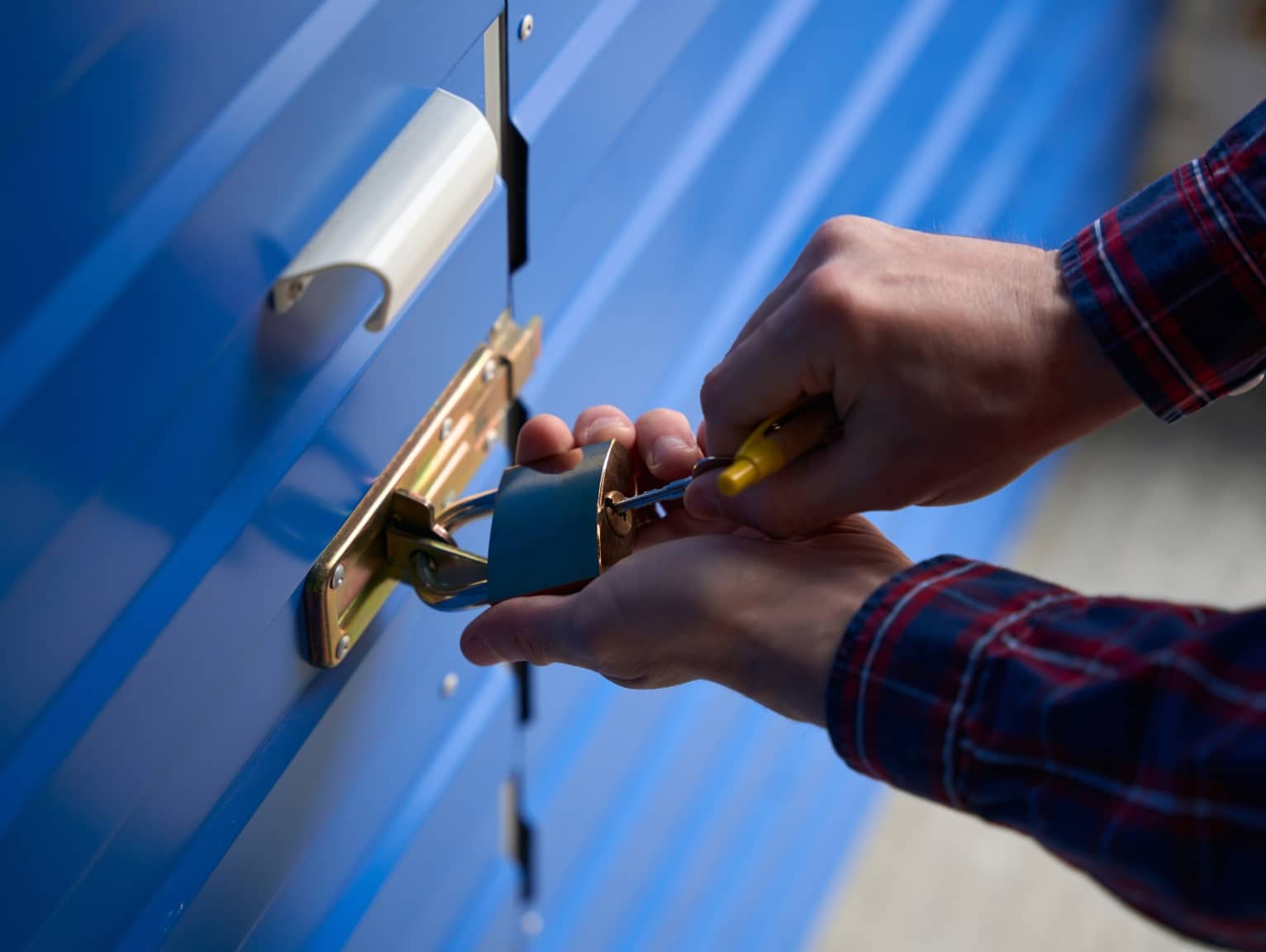 Person securing a blue shipping container with a padlock